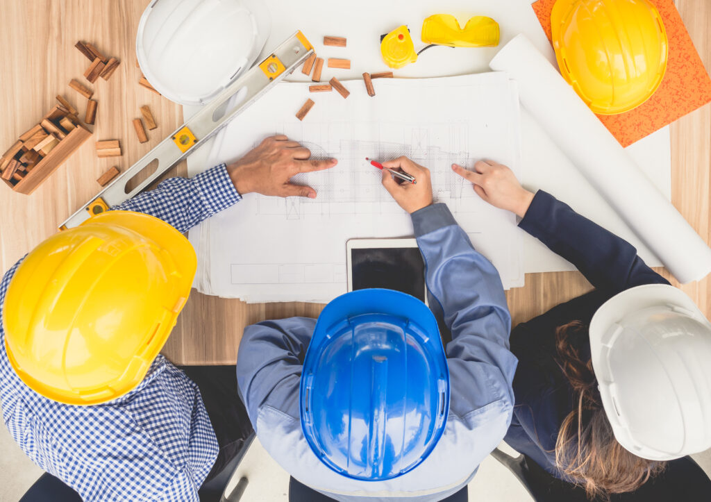Sector Insights group of engineers and architects discussing on table with drawing/blueprint, wearing safety helmet working for industrial construction and engineering